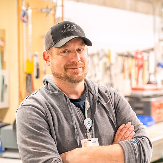 CRMC staff folding his arms and smiling in his workplace.