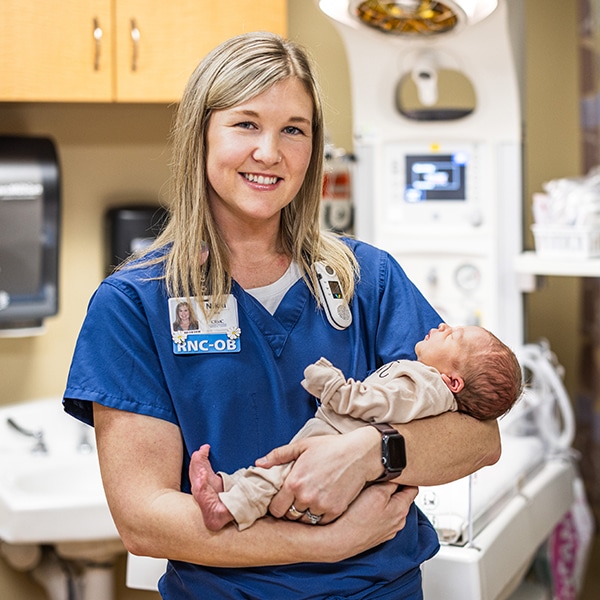 Nurse holds new born baby.