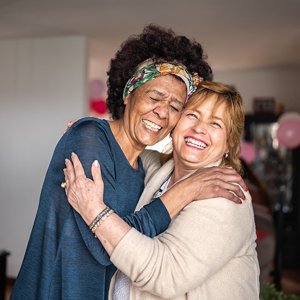 Portrait Of Senior Friends Embracing At Home