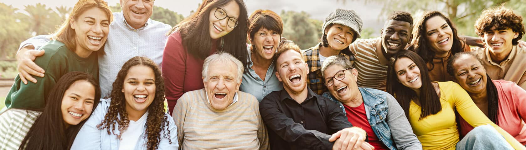 Happy Multigenerational People Having Fun Sitting On Grass In A Public Park