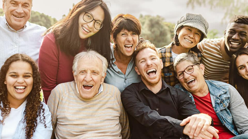Happy Multigenerational People Having Fun Sitting On Grass In A Public Park