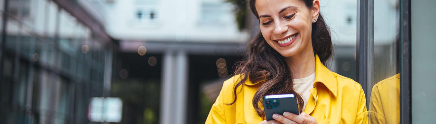 Female Business Professional Walking Outside And Texting From Her Mobile Phone.