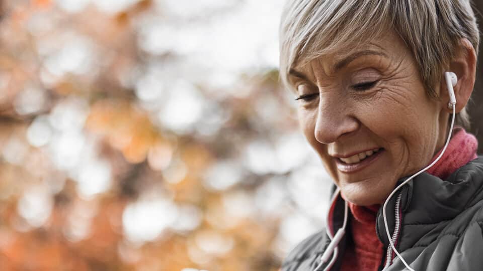Senior Woman Looking At Smart Watch Wearing Headphones