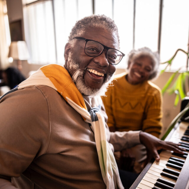 Portrait Of A Mature Man Playing Piano With His Wife At Home