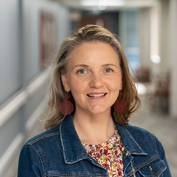 Ashley Krantz, MA, LPCC, smiling in a hallway at the medical campus.