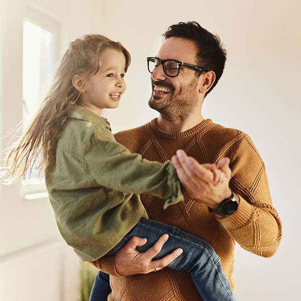 Father smiling and holding his young daughter, representing the comfort of receiving support for financial relief.