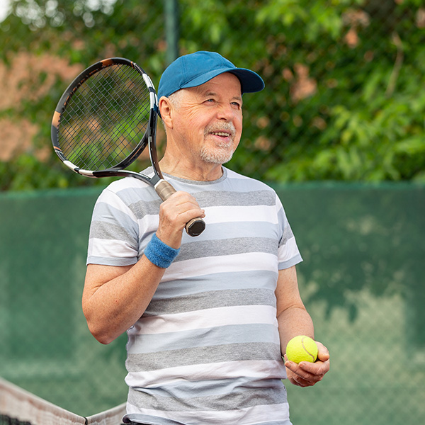 Active older adult playing tennis, representing improved mobility and pain relief from foot and ankle care at CRMC.