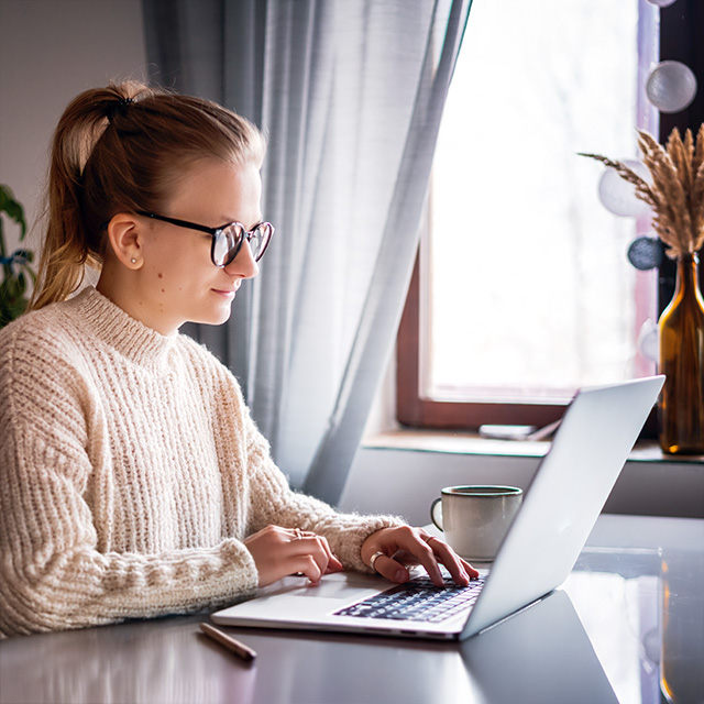 Woman using a laptop at home, representing the convenience of applying online for CRMC financial assistance.