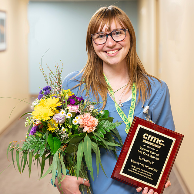 Samantha Henrichs accepting the Trophy Fish Award while holding a bouquet of flowers.