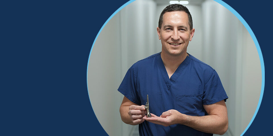 Dr. Stephen C. Schmid holding a custom 3D-printed titanium fibula implant at CRMC
