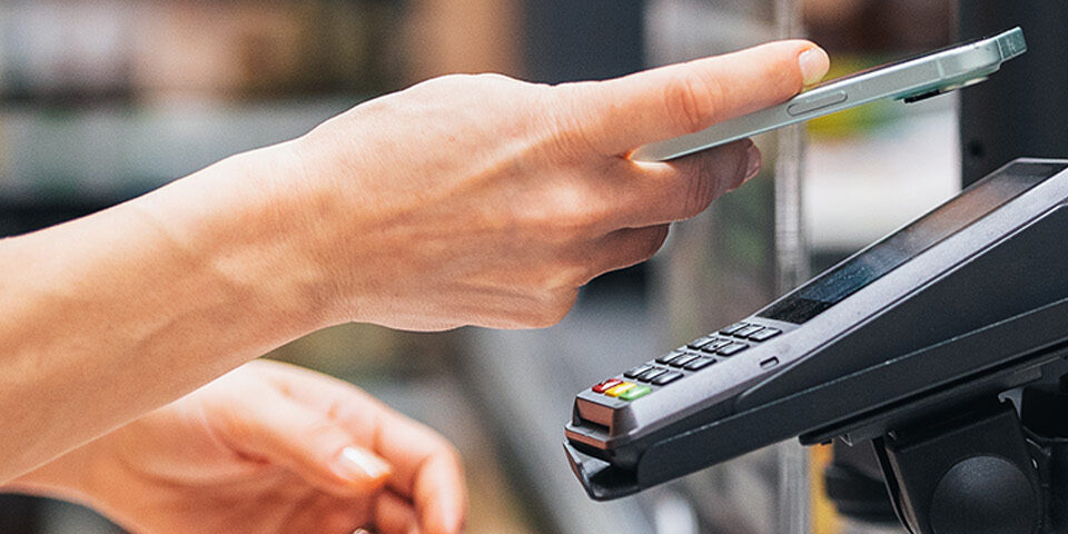 Shopper using a smartphone to pay at checkout, symbolizing the CRMC Foundation’s round-up campaign at Super One stores to support local patients in need.