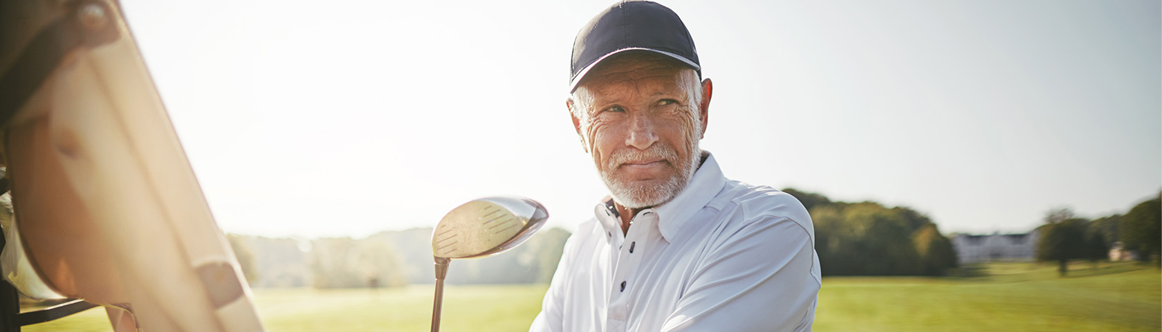 Smiling middle-aged man golfing outdoors, representing the active, everyday life many patients return to with the help of urology care.