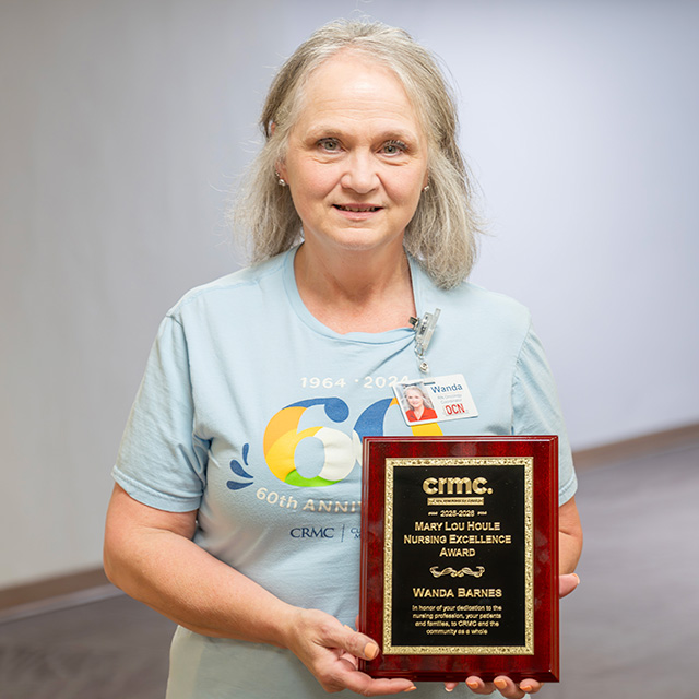Wanda Barnes smiles while holding the Mary Lou Houle Award.