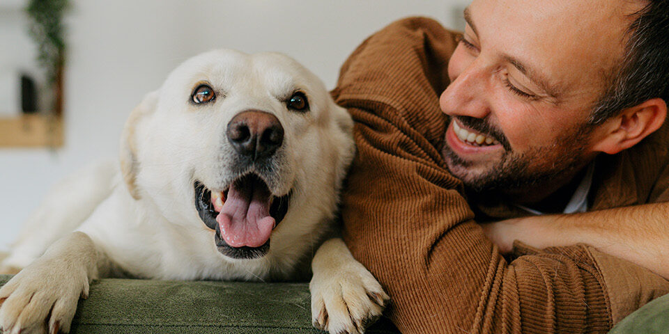 Man smiling joyfully with his dog, representing emotional healing, connection, and happiness in life after opioid recovery.