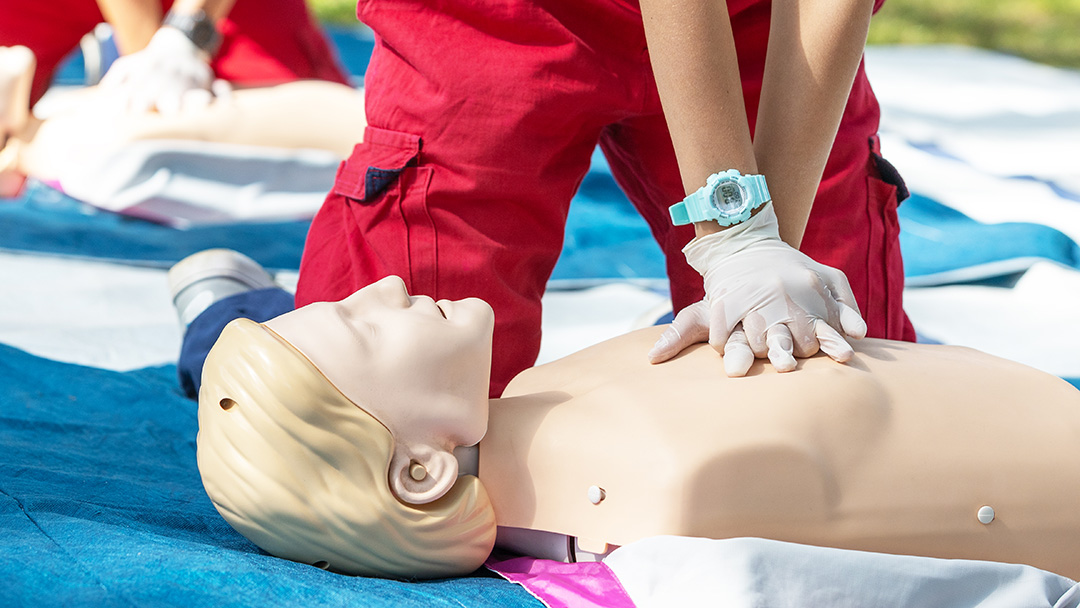 Instructor demonstrating CPR chest compressions on a training mannequin during First Aid, CPR, and AED certification class at CRMC.
