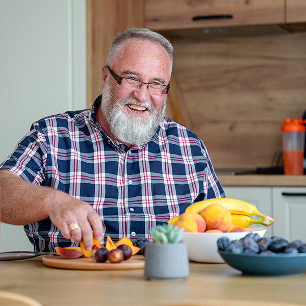Smiling older man enjoying fresh fruit, cured from gastroesophageal reflux disease and able to eat comfortably.