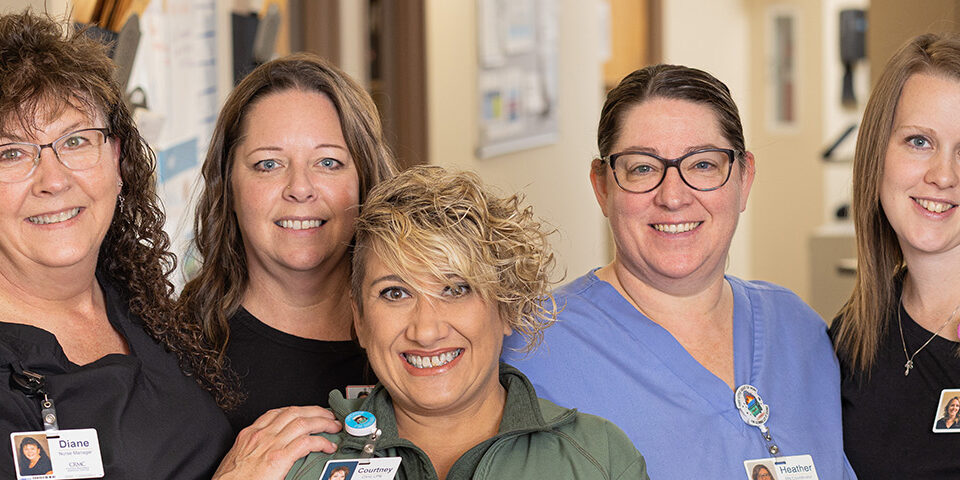 Group of five smiling nurses at Cuyuna Regional Medical Center standing together in a hospital hallway, representing CRMC’s 5-star rating for nurse communication from CMS.
