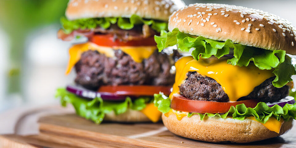 Two juicy Bonk Burgers—Dr. Cady’s signature recipe from Cuyuna Regional Medical Center—topped with melted cheese, lettuce, tomato, and onion on sesame seed buns.