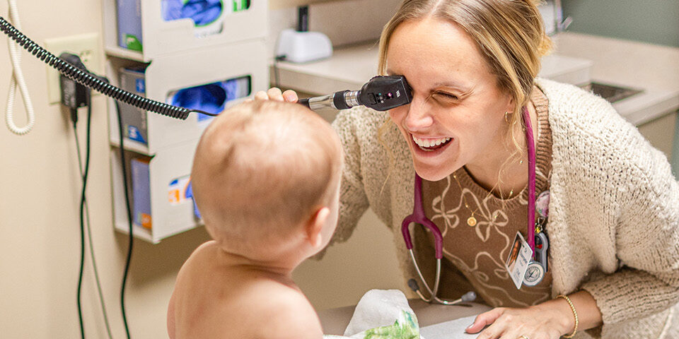 Dr. Hannah Elsenpeter performs an eye exam on an infant during a pediatric visit at CRMC, reflecting compassionate, patient-centered care.