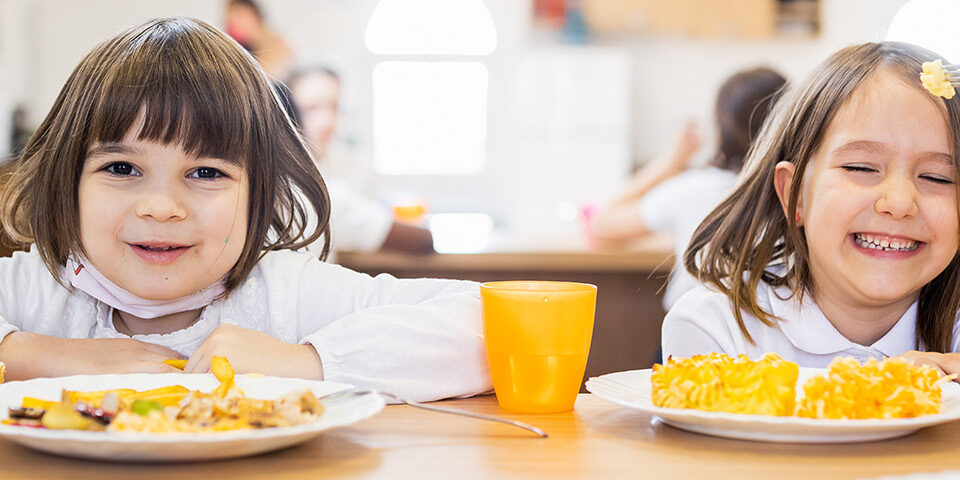 Children eating a healthy meal together at a table, representing nutrition, access to food, and community health priorities outlined by CRMC.