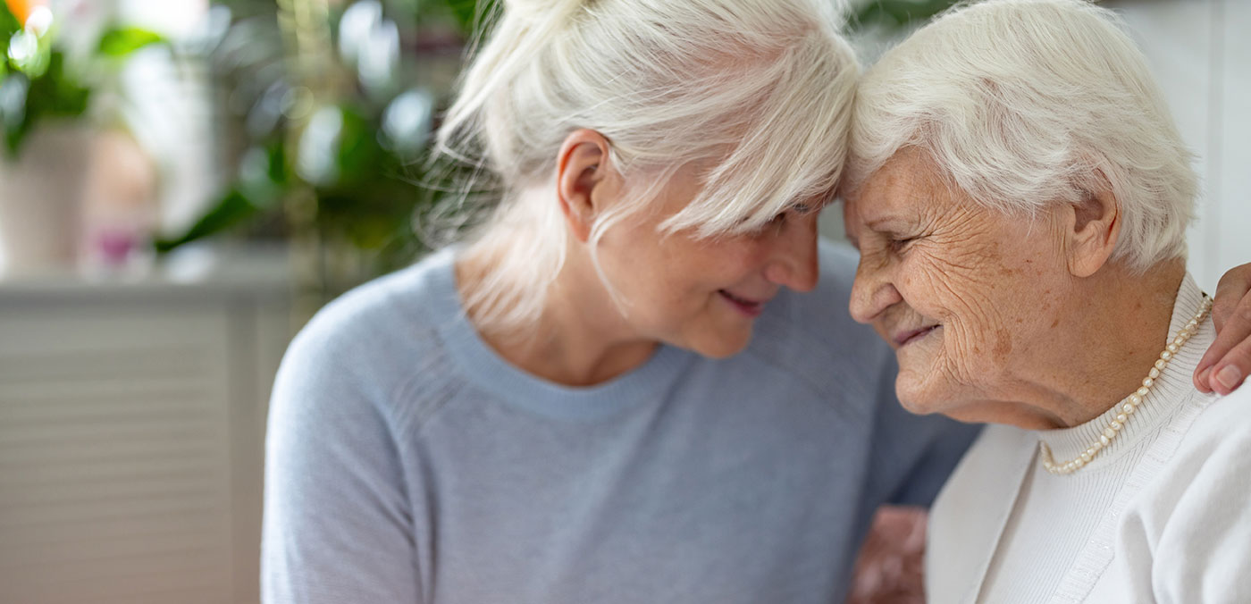 Caregiver comforting an older woman at home, representing support, compassion, and partnership in caring for a loved one with dementia.